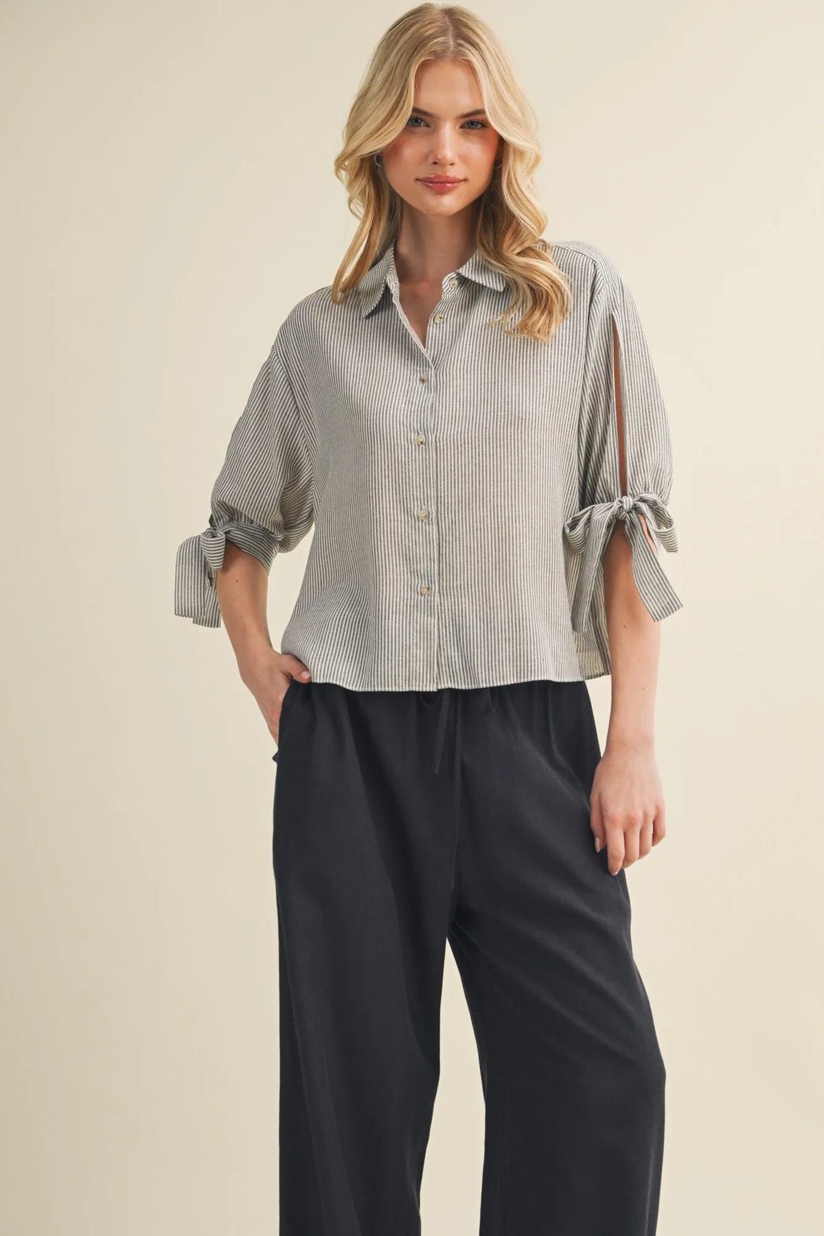 A soft light gray and white striped tie cuff button front top with rolled cuffs tied in bows