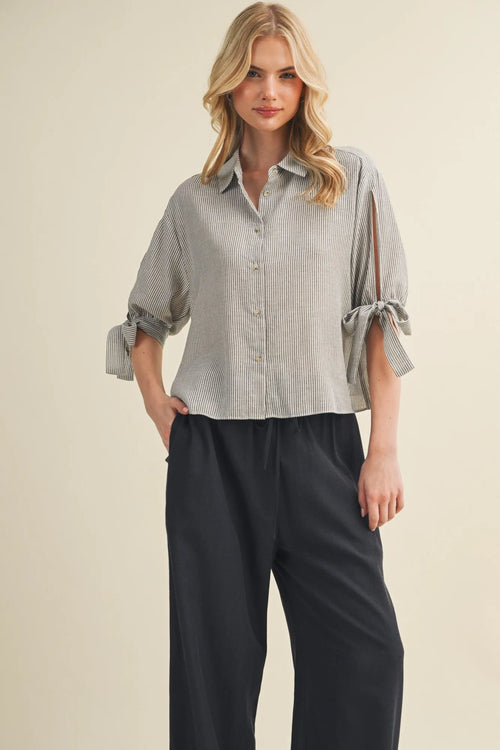 A soft light gray and white striped tie cuff button front top with rolled cuffs tied in bows
