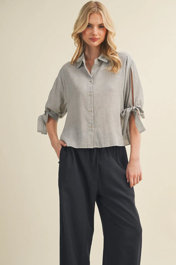 A soft light gray and white striped tie cuff button front top with rolled cuffs tied in bows