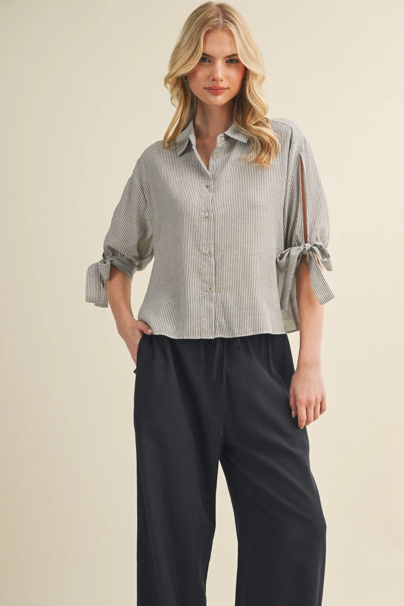 A soft light gray and white striped tie cuff button front top with rolled cuffs tied in bows
