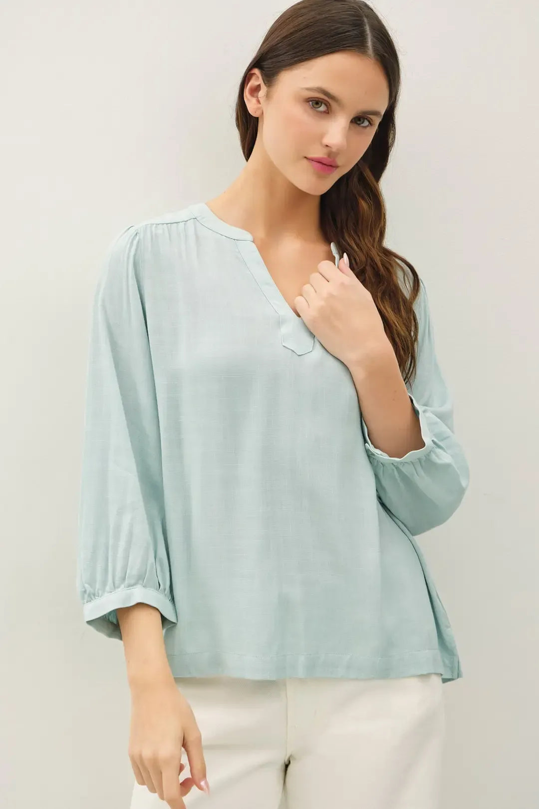 A soft mint green blouse featuring a notched y-neck volume sleeve and puffed three-quarter sleeves