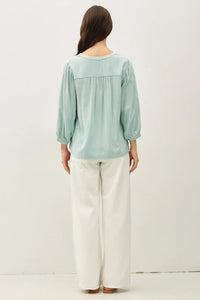 A soft mint green blouse with notched y-neck volume sleeve and gathered waistband for elegant wear