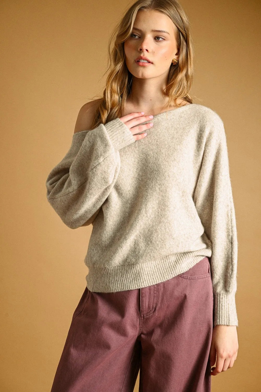A soft beige knit long sleeve boat neck top sweater with relaxed fit ribbed cuffs and off the shoulder design