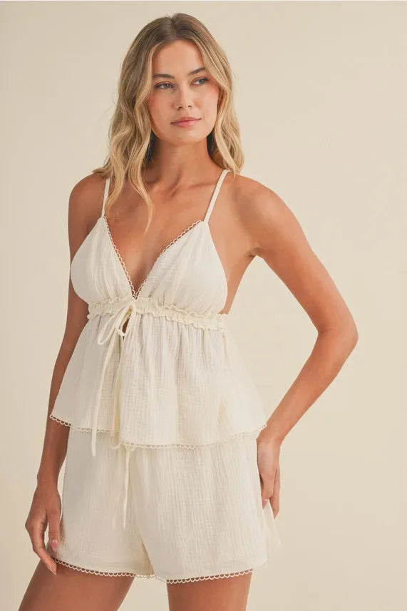 A soft off-white layered romper with gauze picot lace trim and a tied waistband featuring a lace v neck design