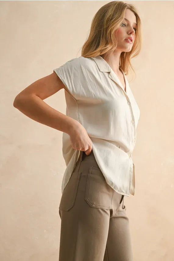 A soft off-white satin lightweight button down cap sleeve shirt with a relaxed fit and short sleeves