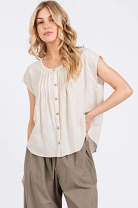 A soft off-white sleeveless blouse with pintuck detailed button closure and pleated front for elegant wear