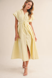 A soft pale yellow poplin short sleeve belted maxi dress with v-neckline and flowing midi length