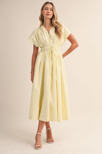A soft pale yellow poplin short sleeve belted maxi dress with v-neckline and pleated flowing midi skirt
