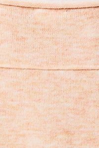 A soft peach-colored knit fabric with ribbed detailing on a contrast trim boat neck oversized knit sweater