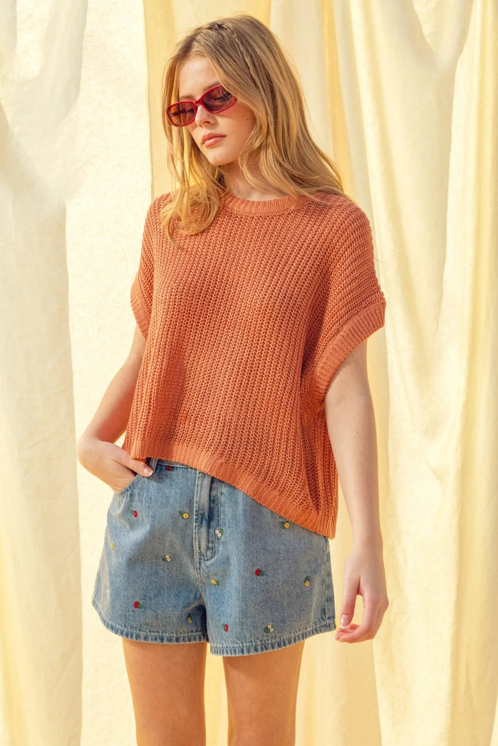 A rust-orange soft ribbed dolman sleeve knitted top with short sleeves and a relaxed fit