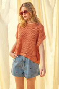 A rust-orange soft ribbed dolman sleeve knitted top with short sleeves and a relaxed fit