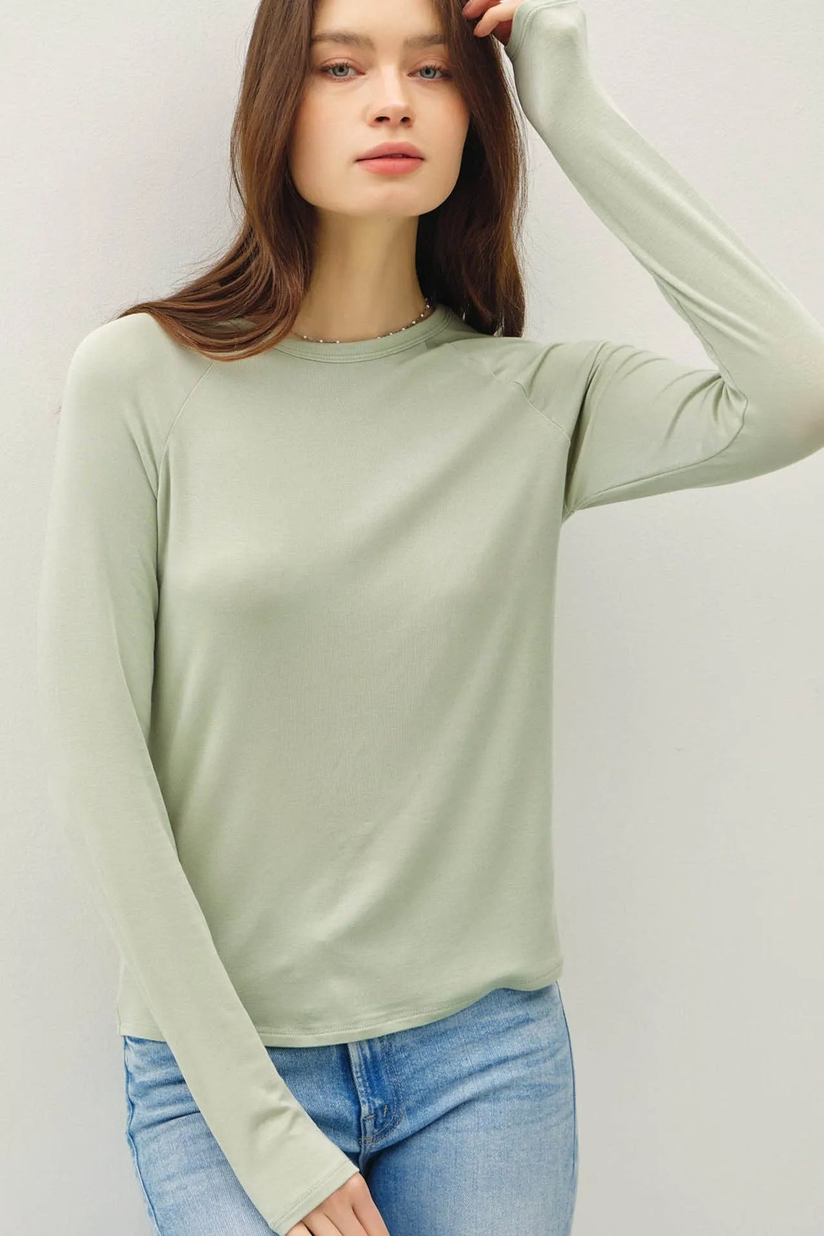 A soft sage green modal raglan sleeve layering basic top with crew neckline and smooth stretchy fabric