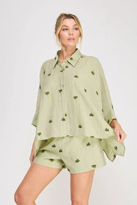 A soft sage green palm tree crinkled woven blouse with a relaxed silhouette and delicate palm tree embroidery