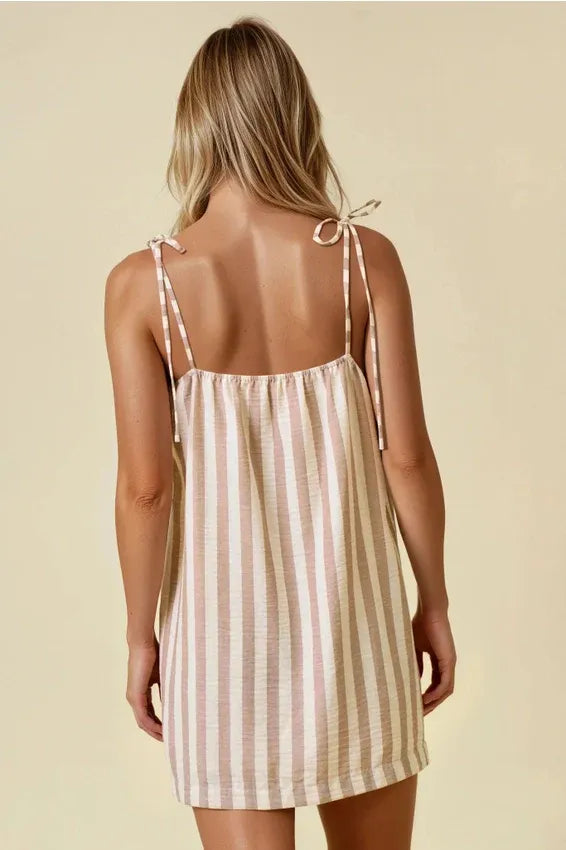 A sleeveless stripe cotton gauze mini dress in muted pink and cream with adjustable tie shoulder straps