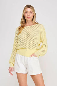 A soft yellow hand yarn open stitch dolman sweater top with a loose fit diagonal ribbed pattern and cropped hem