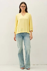 A soft yellow lightweight blouse with a notched y-neck volume sleeve and three quarter length sleeves