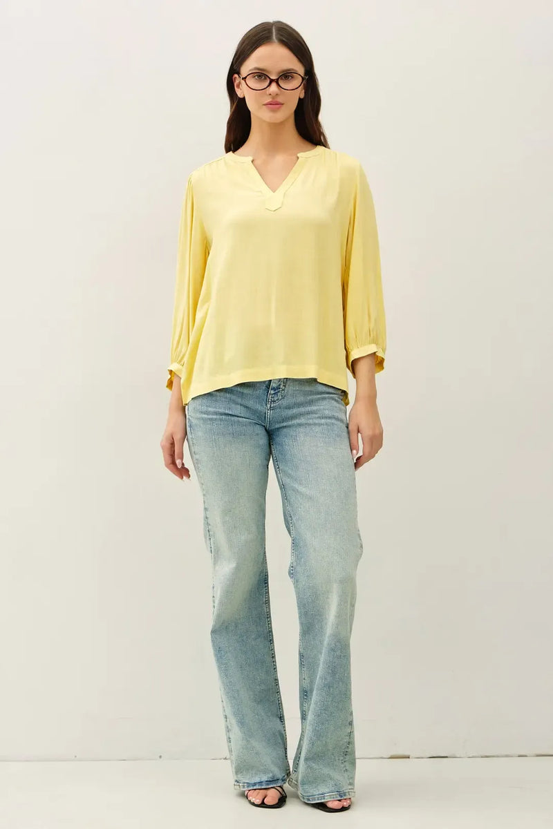 A soft yellow lightweight blouse with a notched y-neck volume sleeve and three quarter length sleeves