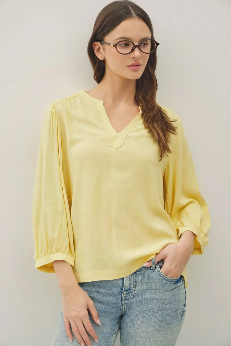 A soft yellow lightweight blouse with notched y-neck volume sleeve and puffed three-quarter y-neck volume sleeve