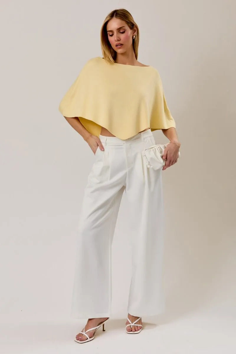 A soft yellow poncho knit top featuring a slouchy neck line and flowing cape-like sleeves for elegant wear