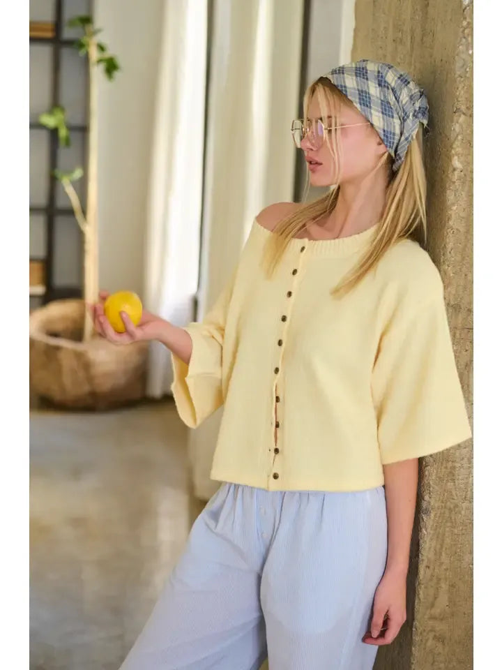 A soft yellow knit wide sleeve button front cardigan with off the shoulder design and button detailing down the front