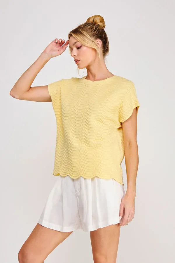 A soft yellow scallop pattern relaxed knit top with short sleeves textured with a wavy pattern and scalloped hem