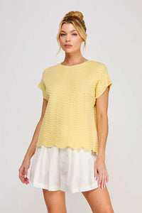 A soft yellow scallop pattern relaxed knit top with short sleeves and a scalloped hem for casual wear