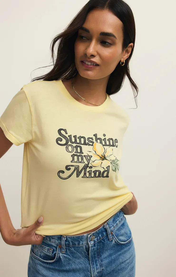 A soft yellow shine tourist tee shirt with short sleeves featuring vintage text and embroidered flower design