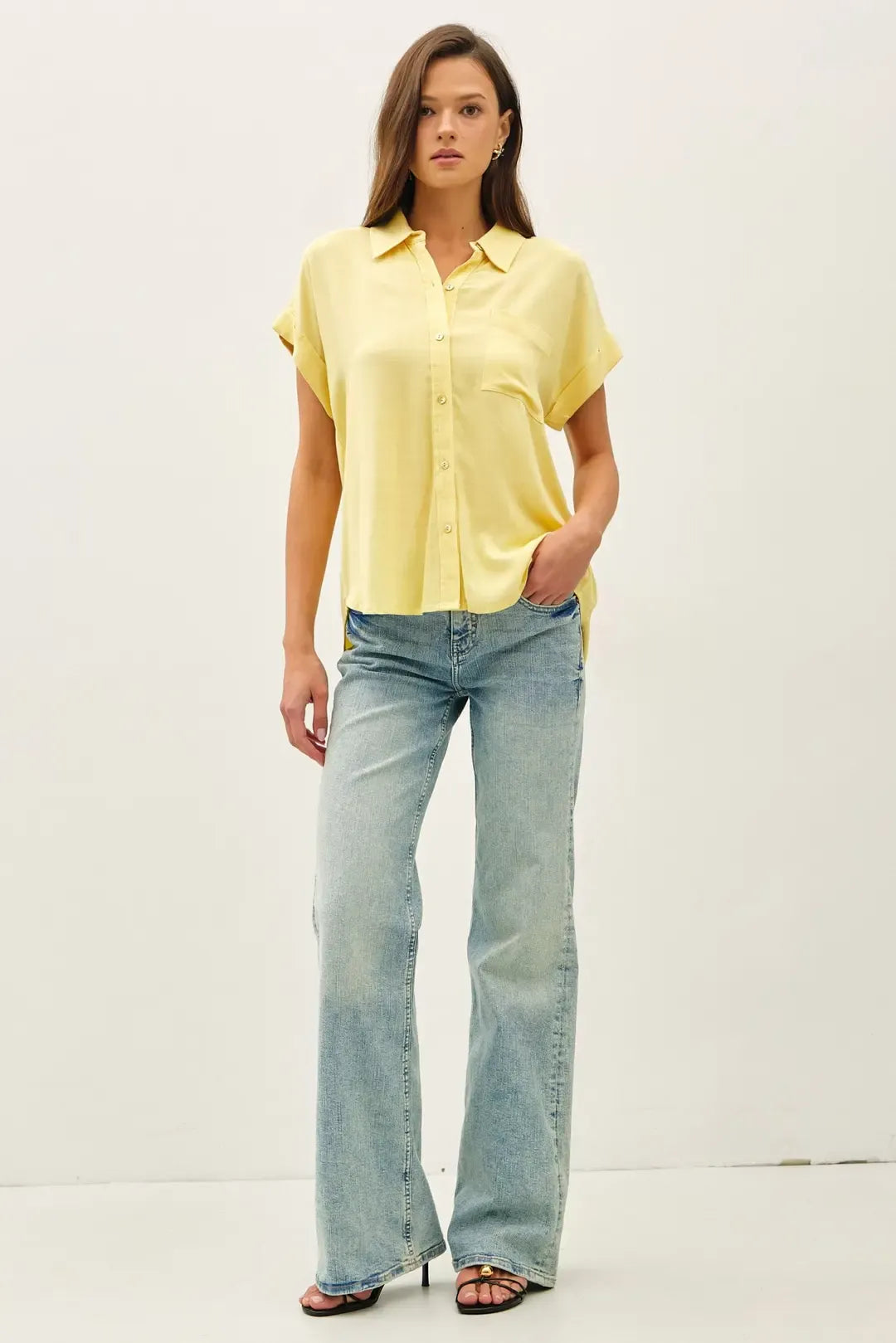 A soft yellow solid short sleeve button down shirt with classic collar and subtle front pleats in high low style