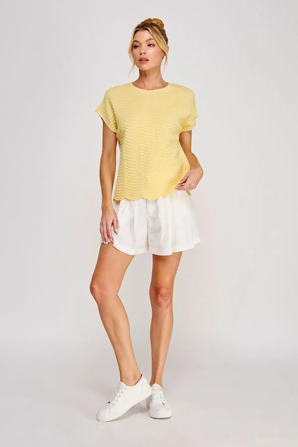 A soft yellow scallop pattern relaxed knit top with short sleeves and a textured scalloped hem