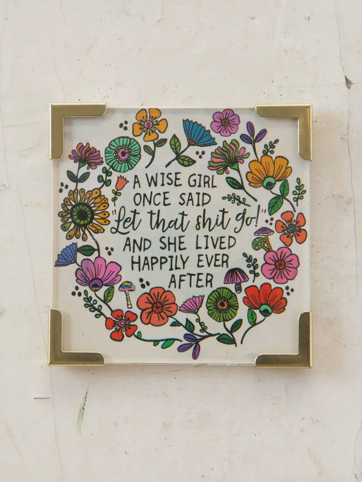 A square decorative glass corner magnet with gold metal frame featuring colorful flowers and a wise girl quote