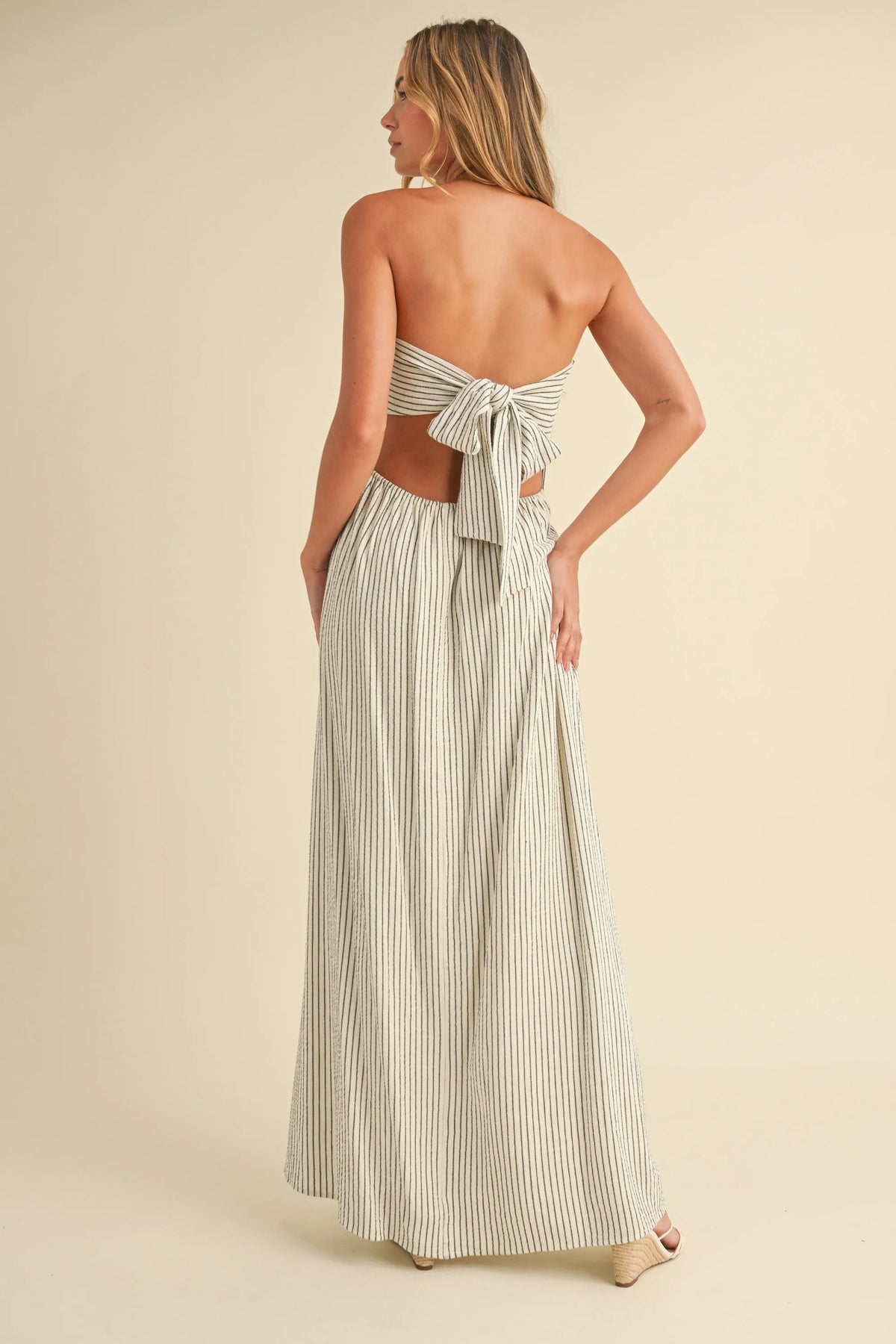 A strapless maxi dress with a back tie in cream and dark gray vertical stripes ideal for elegant occasions