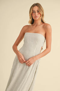 A white and black vertical pinstripe strapless maxi dress with side cutouts and a long back tie detail