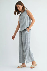 A woman wears soft gray stripe straight leg elastic pants with thin white vertical stripes and a matching sleeveless top