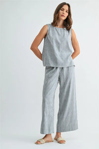 A woman wearing light blue and white vertical stripe straight leg elastic linen blend pants with a sleeveless top