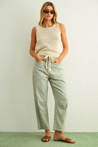Striped wide-leg trousers in soft green and white vertical pattern with drawstring waist paired with sleeveless roundneck knitted top