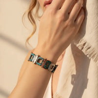 A stylish turquoise and silver-toned patina geometric stretch bracelet with intricate metal links worn on a wrist