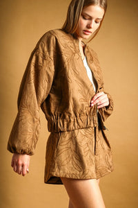 Tan suede bomber jacket with intricate leaf embroidery and elasticated waistband complements suede floral textured shorts