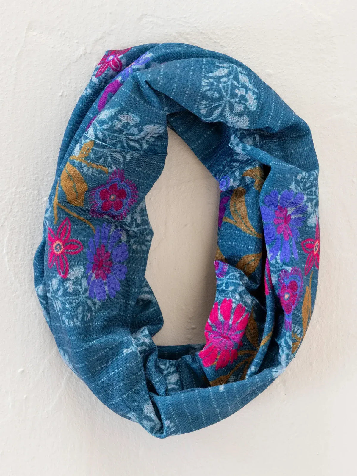 A teal infinity scarf with vibrant pink purple and gold floral pattern complementing a boho bandeau headband block stamp indigo