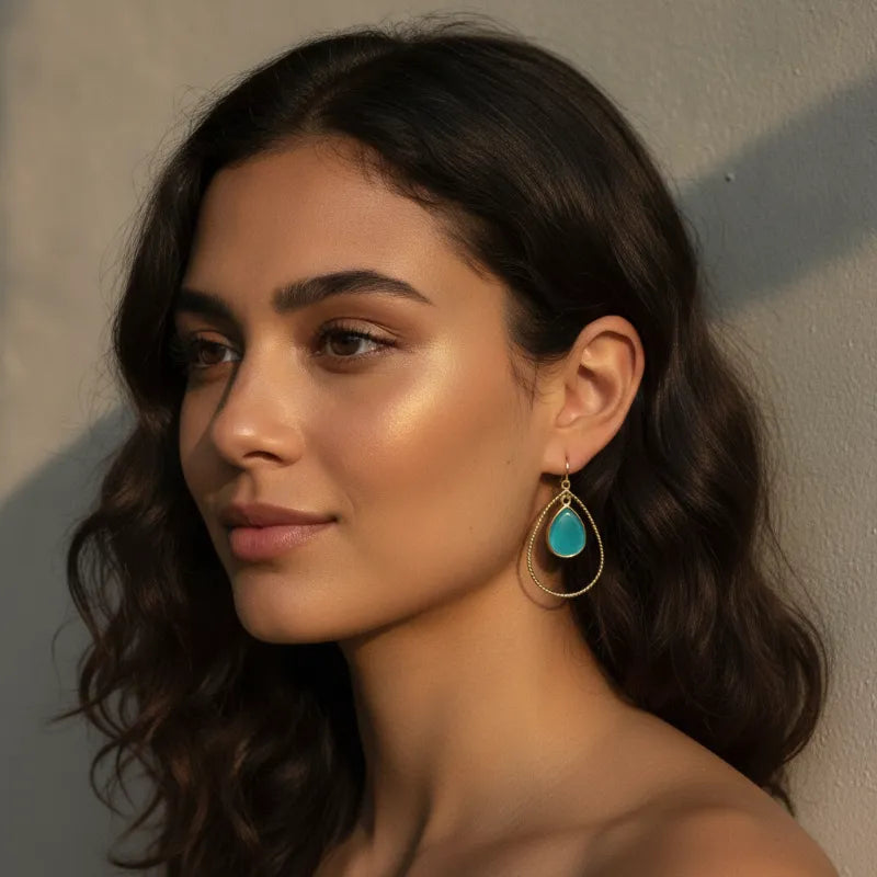 Elegant gold teardrop hoop earrings featuring teal cats eye stone with gold-toned wireframe design