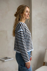 A woman wears a supply dover button cropped long-sleeved sweater with bold black and light blue horizontal stripes