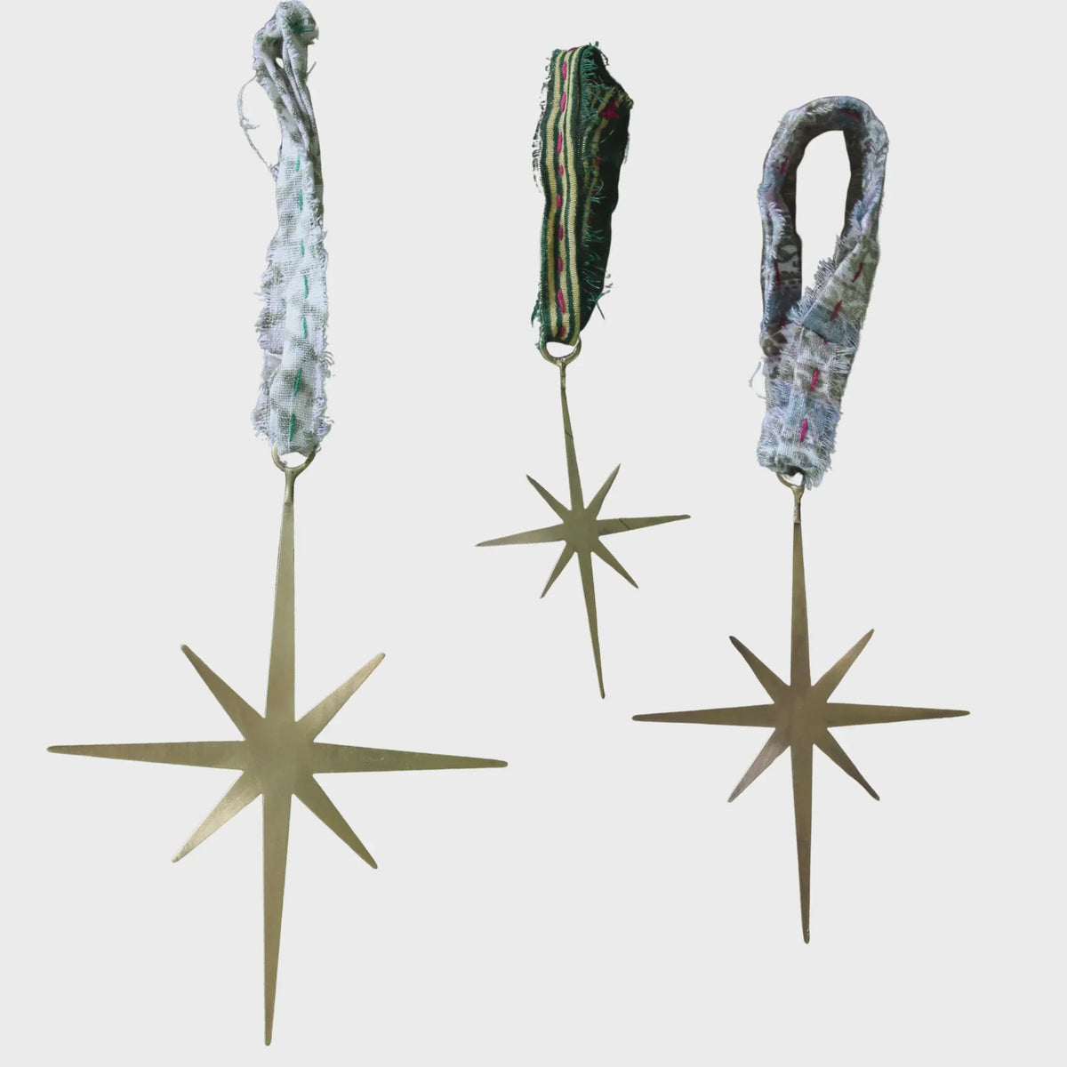 Three north star brass star ornaments with frayed fabric loops in brass finish for decorative use