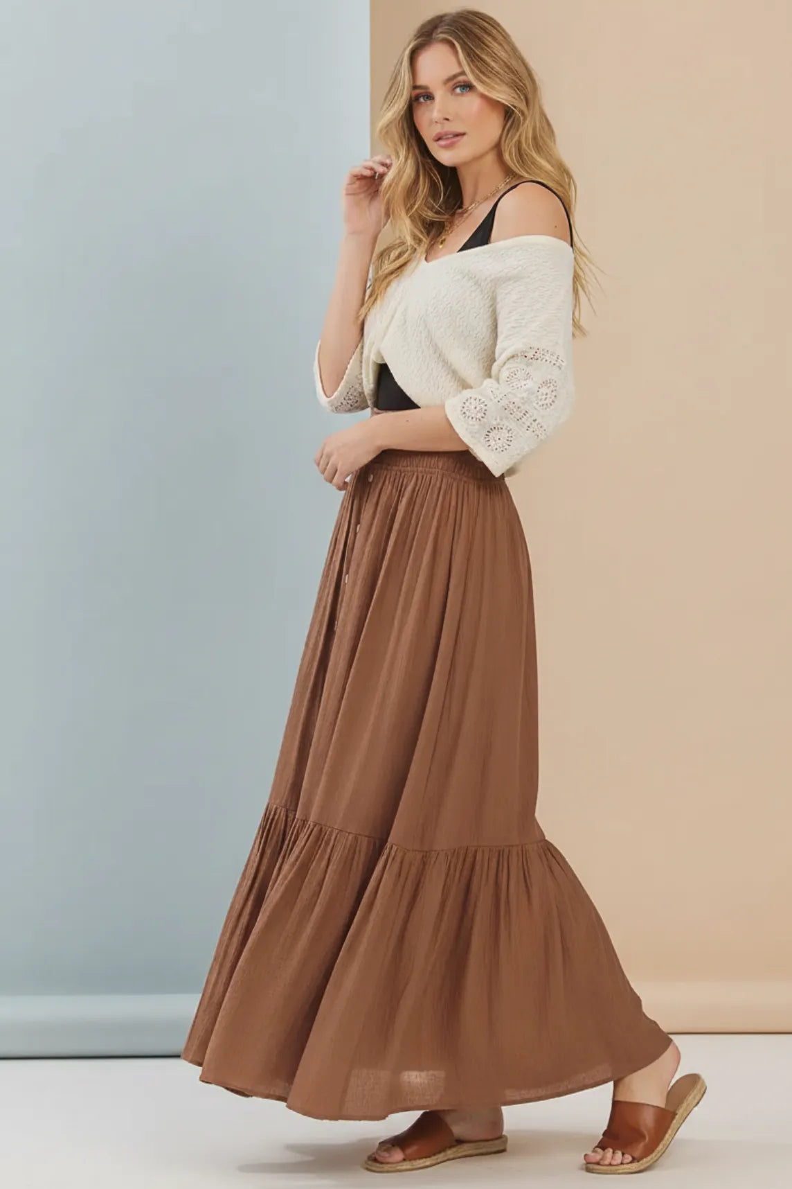 A flowing brown tiered center slit maxi skirt made of lightweight fabric with a soft drape and ruffled hemline