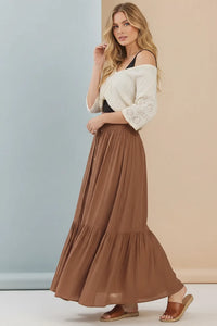 A flowing brown tiered center slit maxi skirt made of lightweight fabric with a soft drape and ruffled hemline