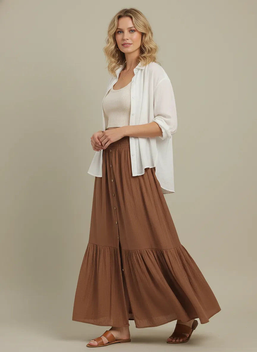 A tiered center slit maxi skirt in brown with soft lightweight fabric and vertical button detailing along the front