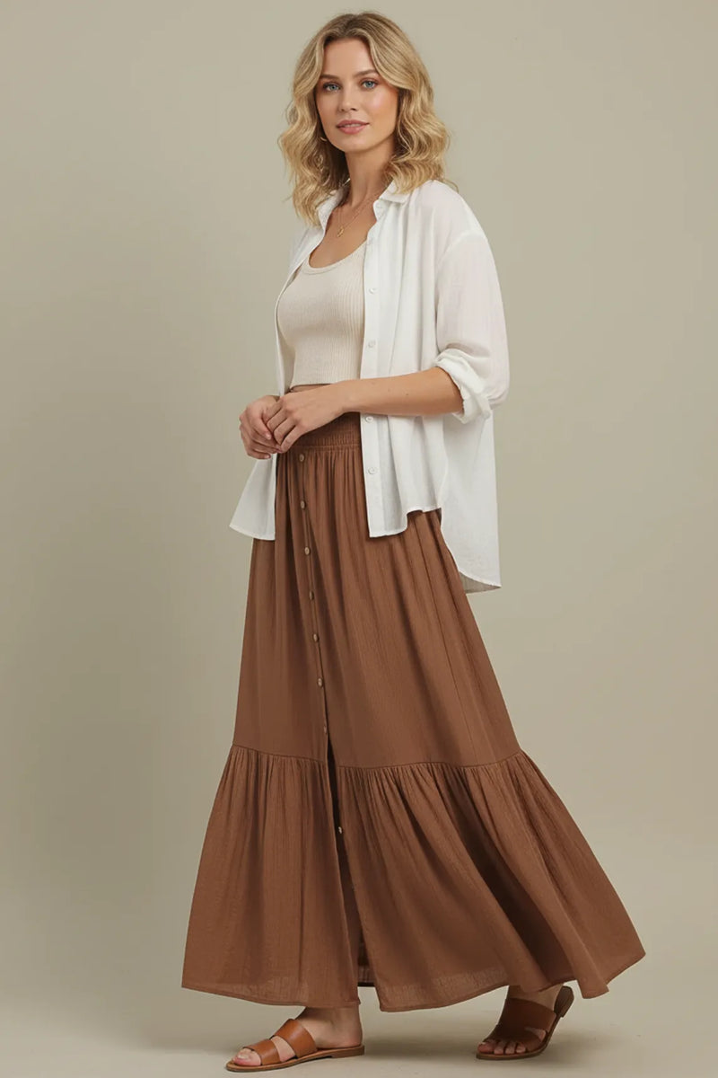 A flowing brown tiered center slit maxi skirt made of soft fabric with a button-front design