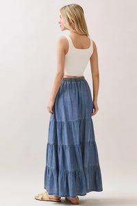 A flowing medium blue wash tencel elastic waisted tiered maxi skirt with subtle fading and frayed hem details