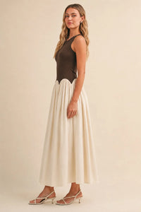 A sleeveless knit crinkle maxi dress with a dark brown fitted bodice and off-white pleated skirt