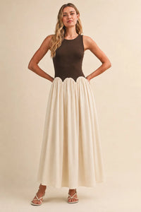 A sleeveless knit crinkle maxi dress with a dark brown fitted bodice and off-white pleated skirt in flowing fabric