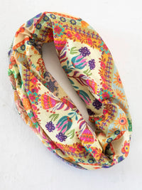 A cream-colored boho bandeau headband with vibrant mandala folk patchwork floral patterns in orange pink purple and teal