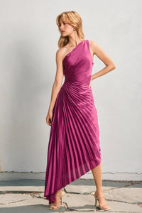 A vibrant magenta satin one shoulder asymmetrical pleated dress with a draped bodice and pleated skirt